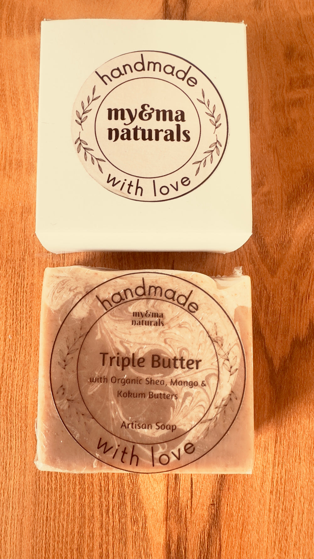 Handmade My & Ma Triple Butter Artisan Soap (110g) with organic Shea, Mango, and Kokum butters in rustic packaging on a wooden surface, providing nourishment for all skin types.